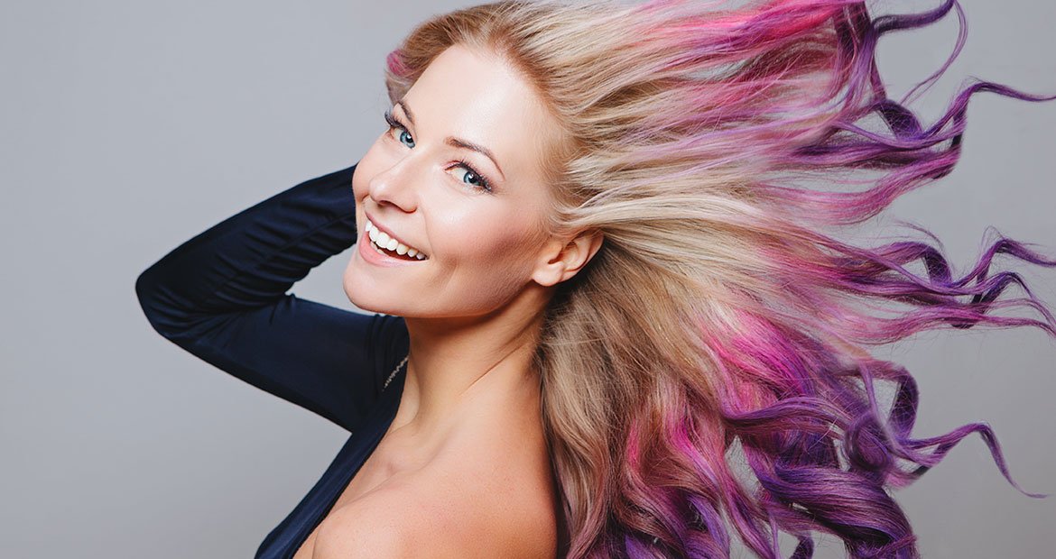 Modelo com longos cabelos loiros com pontas coloridas de rosa e roxo